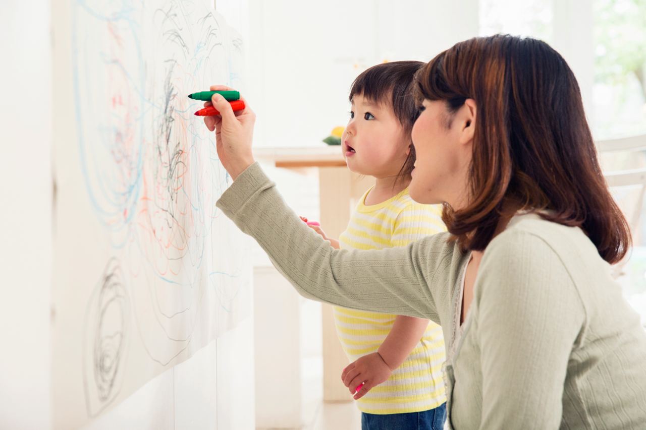 une professionnelle de la petite enfance dessine avec un enfant