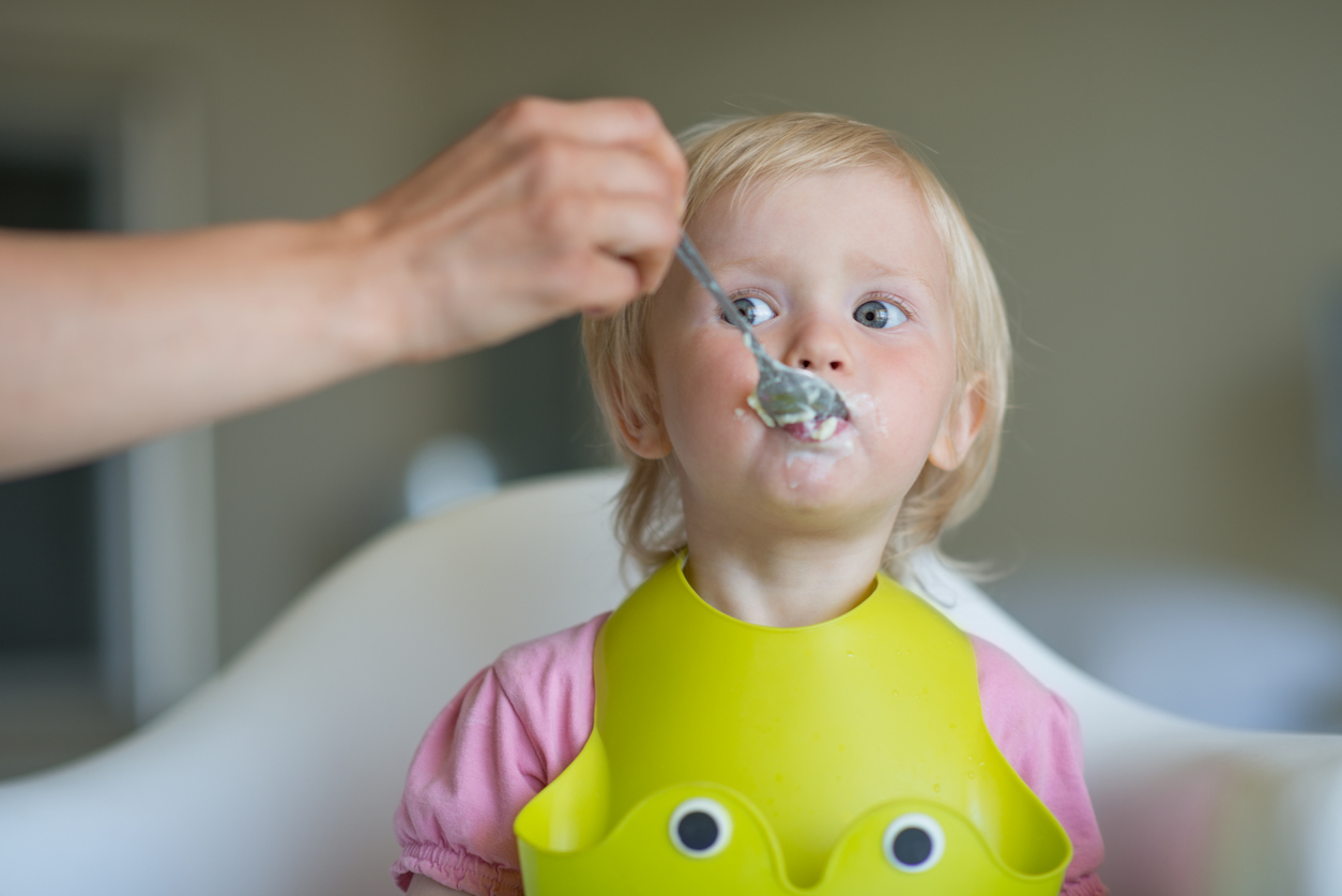 adute donne à manger à un enfant en EAJE