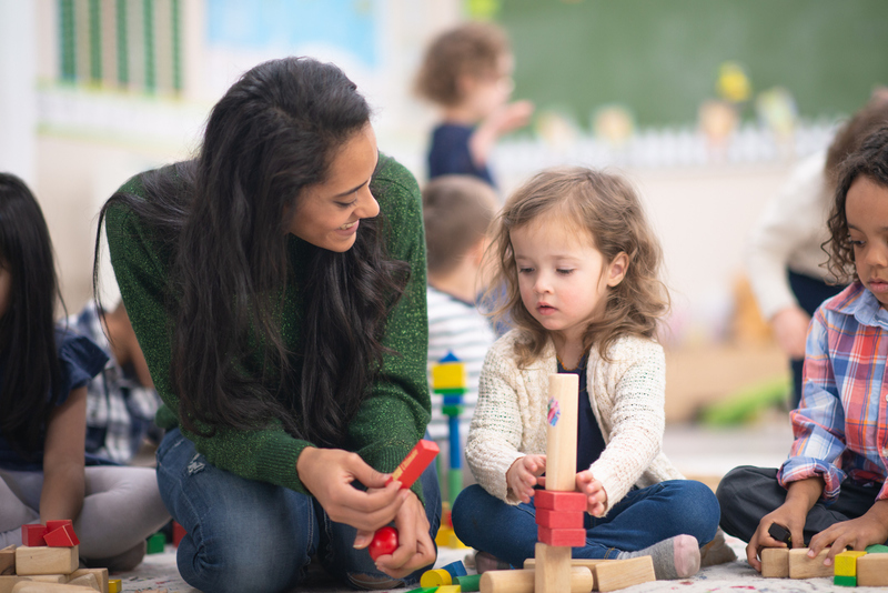 Professionnelle de la petite enfance qui joue avec une petite fille 