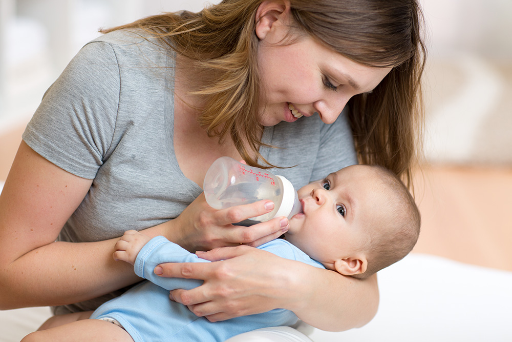 assistante maternelle qui donne le biberon à un bébé