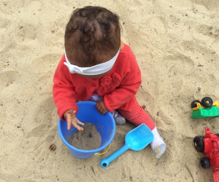 petite fille  les mains dans le sable 