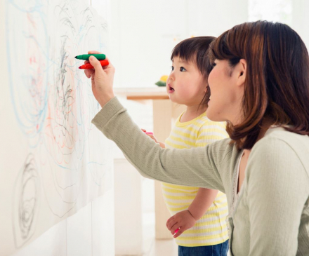 une professionnelle de la petite enfance dessine avec un enfant