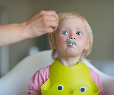 adute donne à manger à un enfant en EAJE