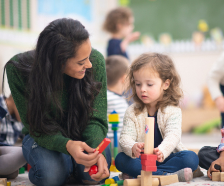 Professionnelle de la petite enfance qui joue avec une petite fille 