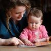 assistante maternelle regarde un livre avec un bébé